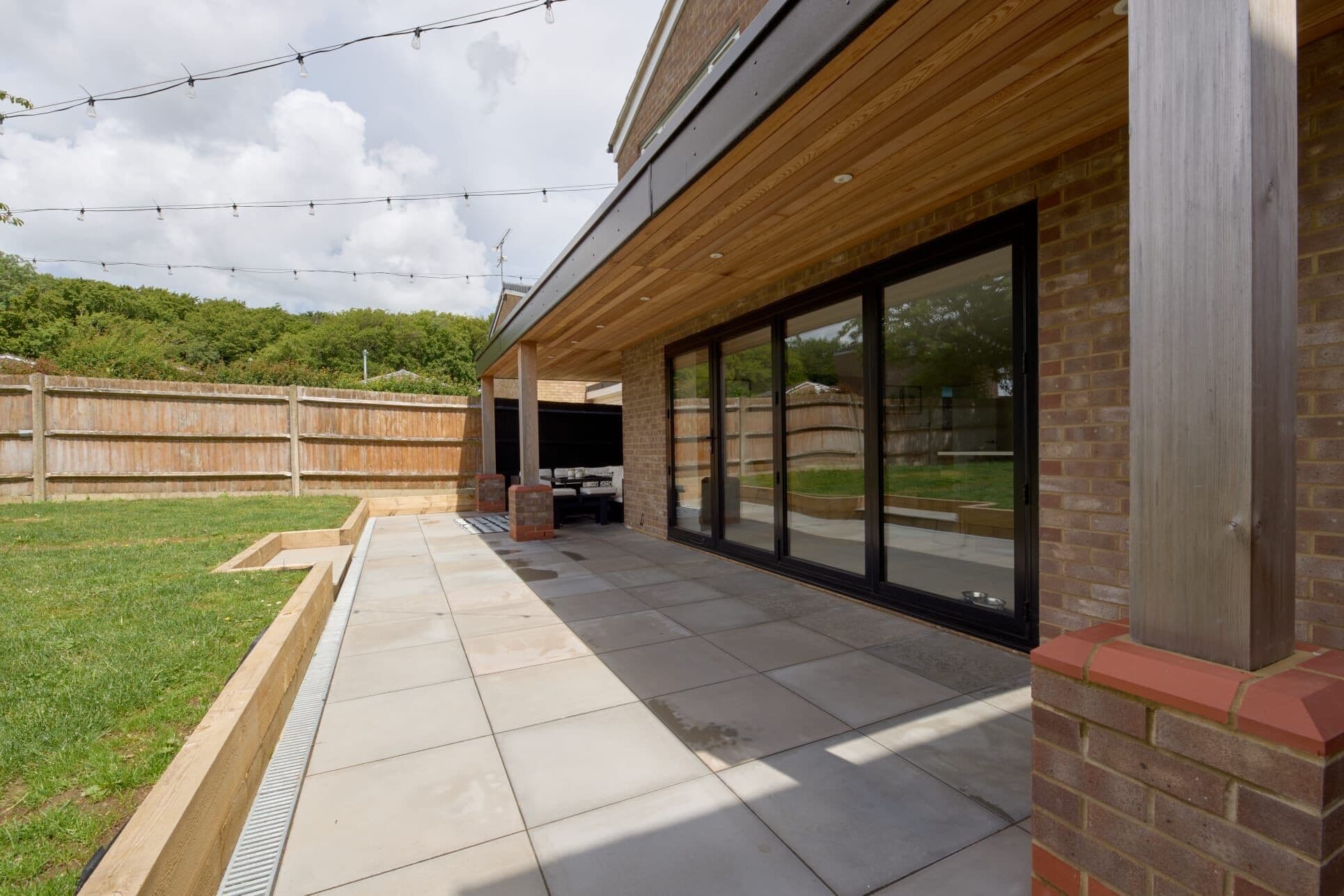 Single storey rear extension with bi-fold doors, covered patio and landscaped garden by DNR Build