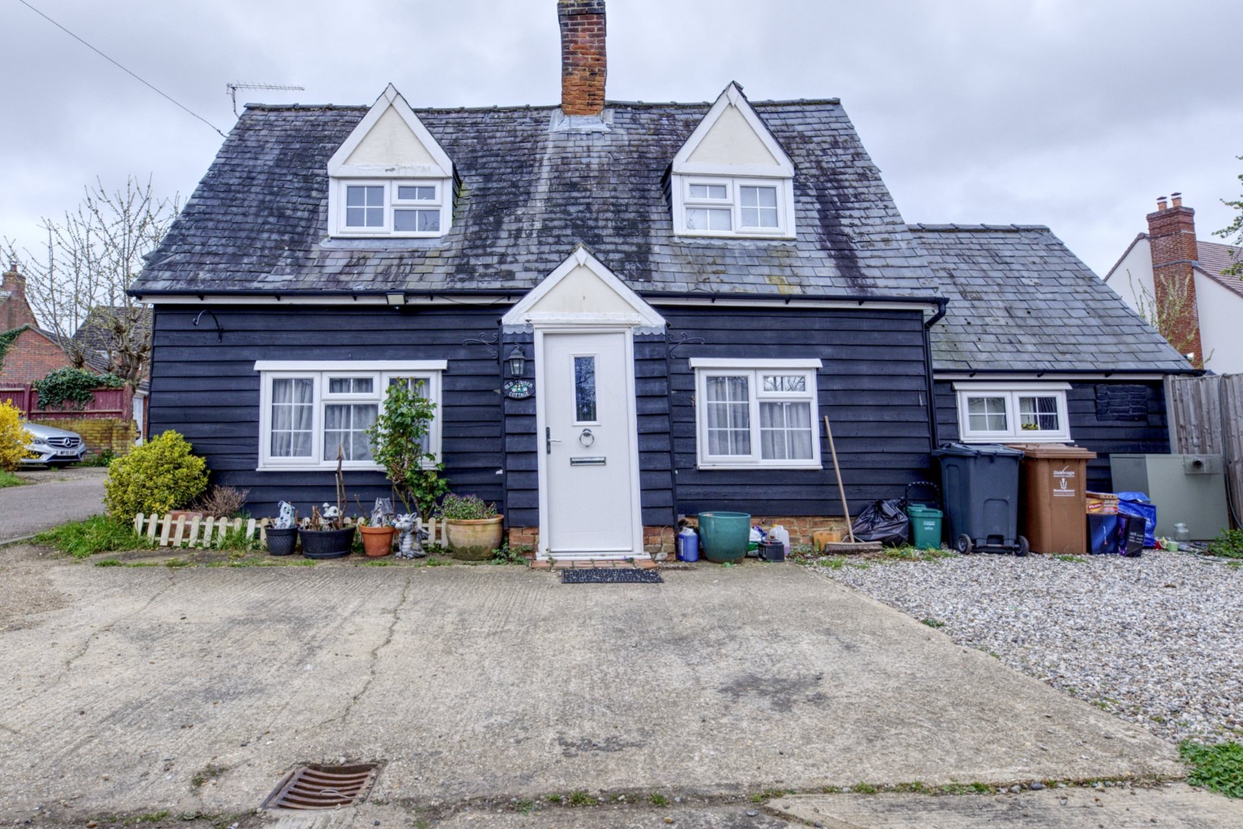 The front of the Old Timber Cottage in Stevenage before the renovation, with its weathered roof, chimney and white porch